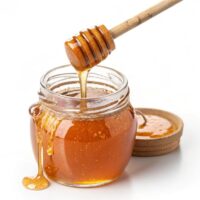 jar of honey with wooden spoon Small Bee vs. Large Bee Honey: The Ultimate Guide to Choti Makhi & Sidr in Pakistan